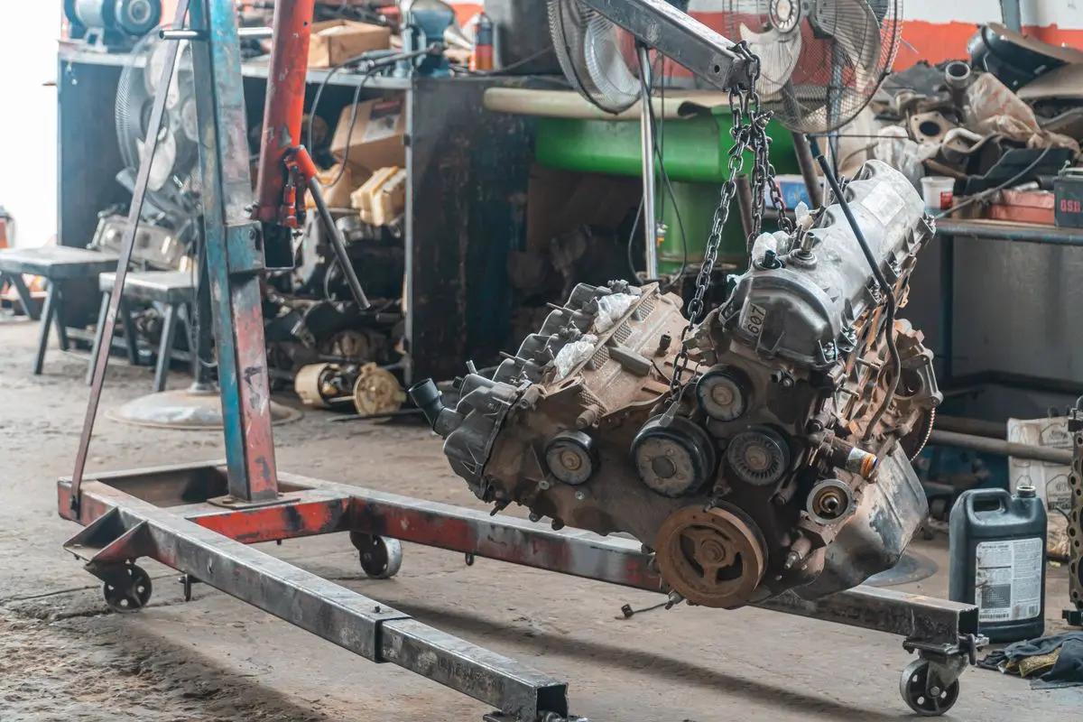 Atölyede motor vincine asılmış, sökülmüş araç motoru